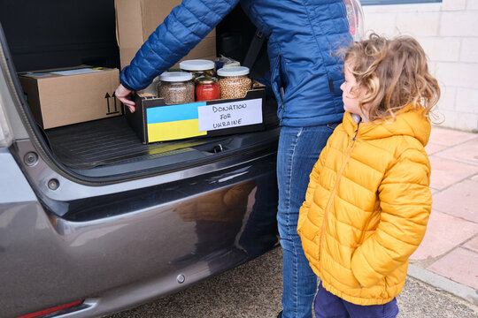 Mother and son taking a box with food to donate to Ukrainian refugees. Humanitarian aid in the Ukrainian war