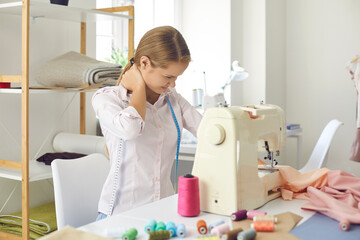 Woman seamstress work on sewing machine in tailor suffer from neck pain sit in incorrect position....