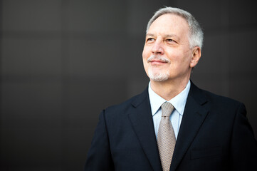 Mature business man portrait outdoor in a happy pensive expression