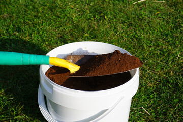 Eimer mit gesammelten Kaffeesatz und einer Schaufel zum Einsatz im Garten