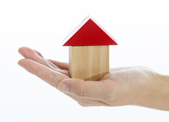 Hand holding toy blocks house on white background