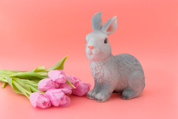 Beautiful pink tulips, rabbit toy and Easter eggs, pink, blue, light blue in a wooden white box. Pink background. Concept illustration of Easter, holiday. Greeting card. Close-up