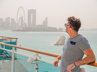 Fashionable man standing on the empty deck of a cruise liner. Closeup, outdoor. Vacation and travel concept