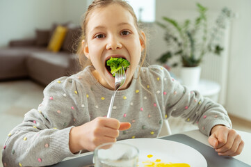 Cute teen girl eating green fresh broccoli