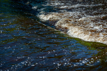 Close up detail of fierce water river rapids from a deep blue colored river forming a textured background. Rough water of spring river.