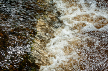 Rough water of spring river. The water boils in rapid flow of river. Close up. Motion blur.