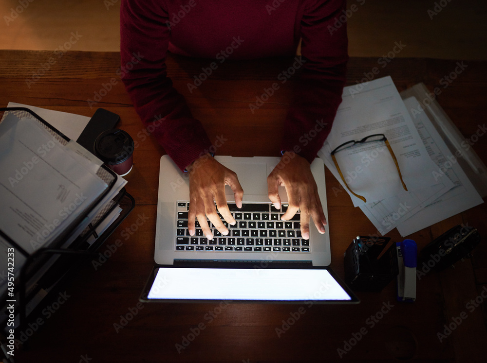 Poster working hard to meet the project deadline. high angle shot of an unrecognizable man working late in 