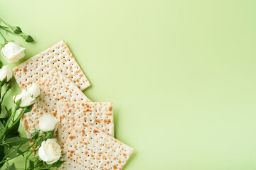 Passover celebration concept. Matzah, red kosher wine, walnut and spring beautiful rose flowers. Traditional ritual Jewish bread on light green background. Passover food. Pesach Jewish holiday.