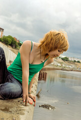 Naklejka premium Red hair woman relaxing on river bank