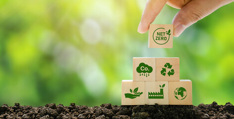 Net Zero and Carbon Neutral Concepts Net Zero Emissions Goals A climate-neutral long-term strategy Ready to put wooden blocks by hand with green net center icon and green icon on gray background. - obrazy, fototapety, plakaty