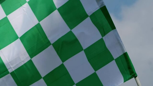 Green checkered racing flag blows in the wind