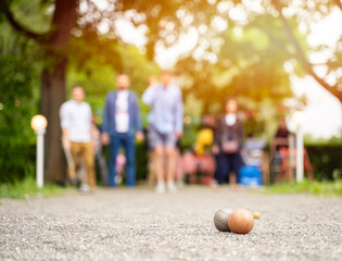 Group of people playing petangue outdoor game guy throw bocce ball in summer park	

