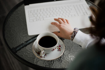 Taza de café al lado de una persona que trabaja en su computadora. Concepto de negocios, estudiante.
