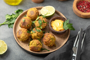 Chickpea falafel with lime and sauce on a plate and grey table