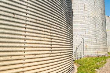 Abstract view of steel grain silo's seen at the edge of a milling facility. Grass can be seen between the silos. © Nick Beer