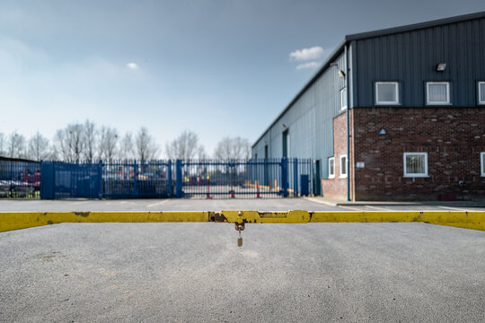 Shallow focus of a yellow single bar gate at the entrance of a business car park. Used to prevent unauthorised parking and nuisance during non work hours.
