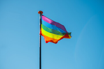 Rainbow flag waving against blue sky