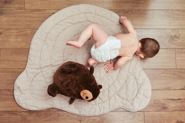 Falling infant baby boy in diapers while crawling or walking. Child first steps and fall to the...