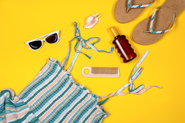 Summer flatlay. Female sandals, stripped viscose sundress, white sunglasses, suntan oil, a pink...