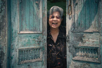 old woman standing near old blue wooden door