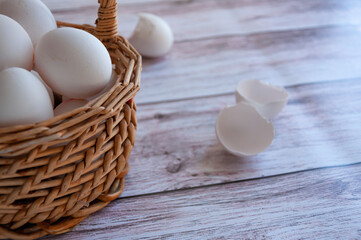 Basket with white eggs. White eggs in a wicker basket. A part of basket with eggs. Simple composition. Spring. Easter.