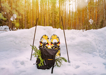 Bright yellow snowshoes in the snow next to the trekking poles and black backpack. Winter hiking...