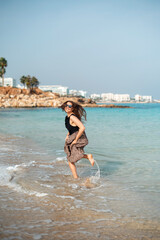 Cheerful woman walking barefoot on sandy beach