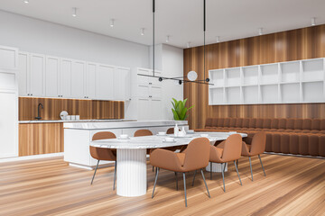 Light kitchen interior with seats and dining table, cooking area and appliances