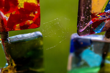 Closeup shot of a spider web between two colored glass pieces