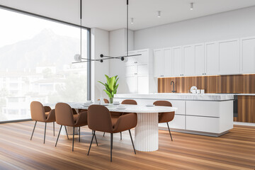 Light kitchen interior with dining table and island, cooking area and window