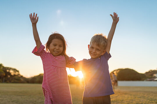 Multi Racial Boy Girl Children Portrait Smiling Happy Standing In An Outdoor Sunset Setting. 