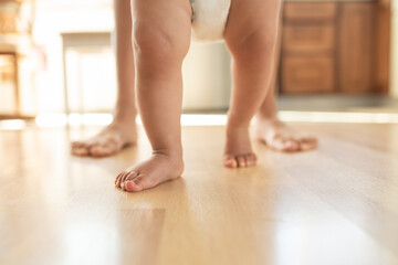 First baby steps. Child learning to walk with mothers help 