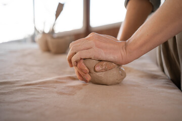 Close-up of female hands of a potter she kneads a piece of raw clay. the concept of favorite hobby is modeling. banner.