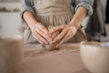 DIY work close-up of a female potter sculpting raw clay before molding pottery in a pottery workshop during a workshop. The concept of craft and craftswoman.