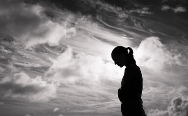 Silhouette of sad woman looking down 