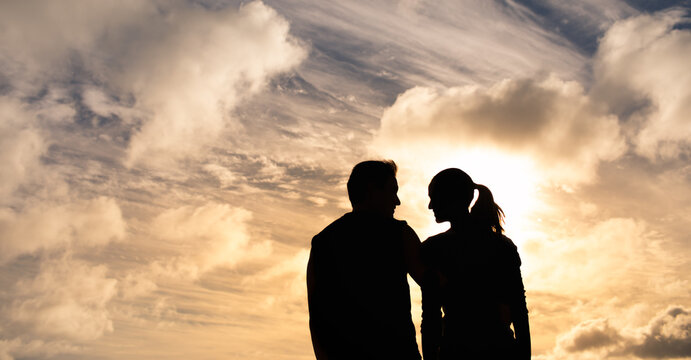 Silhouette of couple together facing the sunset sky. People relationships 