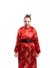 young woman in red oriental costume, looking directly at the camera, shouting and clenching his fists with his arms outstretched against a white background.