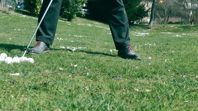 Golfer Training Chipping the Golf Ball on the Grass in a Sunny Day in Switzerland.