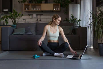 A middle-aged woman at home, engaged in fitness and fog, uses a laptop for online group activities