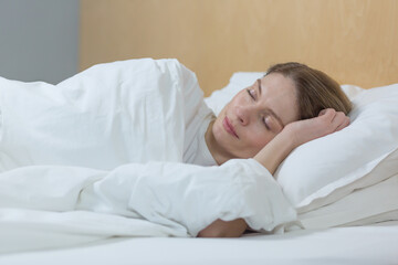 Fototapeta na wymiar Woman sleeping at home under a blanket with eyes closed resting