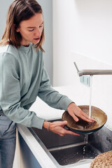 Woman washing dishes in the kitchen sink