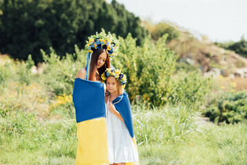 mother and daughter in traditional Ukrainian wreaths blue and yellow flag of Ukraine. Family,...