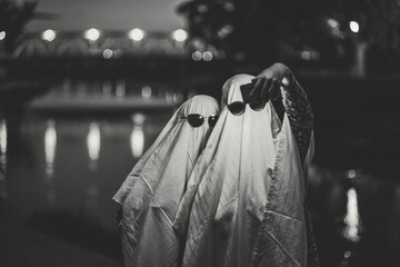 Grayscale funny image of two people in ghost costumes and sunglasses taking a selfie