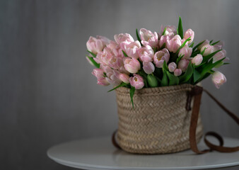 Pink tulips flowers in a basket on the table. Rustic background. Place for text. Selective focus