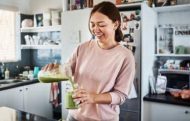 This will get me ready for the day. Cropped shot of a young woman making a smoothie in the kitchen...