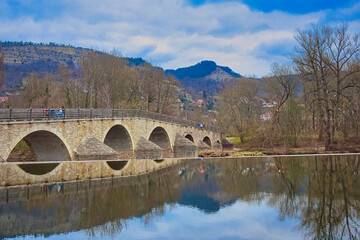 Fototapeta premium Historische Steinbogenbrücke über die Saale mit Spiegelung im Wasser und Blick auf die Kernberge, Alte Burgauer Brücke als Baudenkmal, Jena, Kreisfreie Stadt Jena, Thüringen, Deutschland