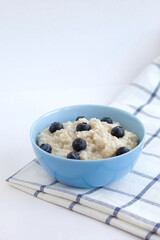 Oatmeal porridge with blueberries in a blue plate on a checkered napkin. Food photography