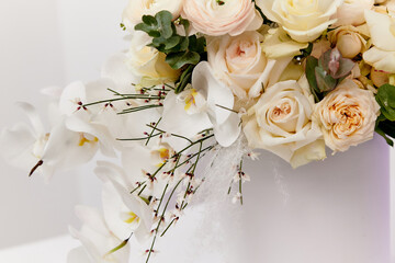 white flowers hang from a box on a white background. white roses in a bouquet with green leaves