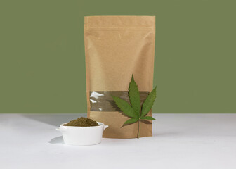 Hemp flour in a brown kraft paper doypack bags with groceries front view on a green background....