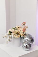 a bouquet of white flowers stands in a white box on a light background along with shiny silver balls